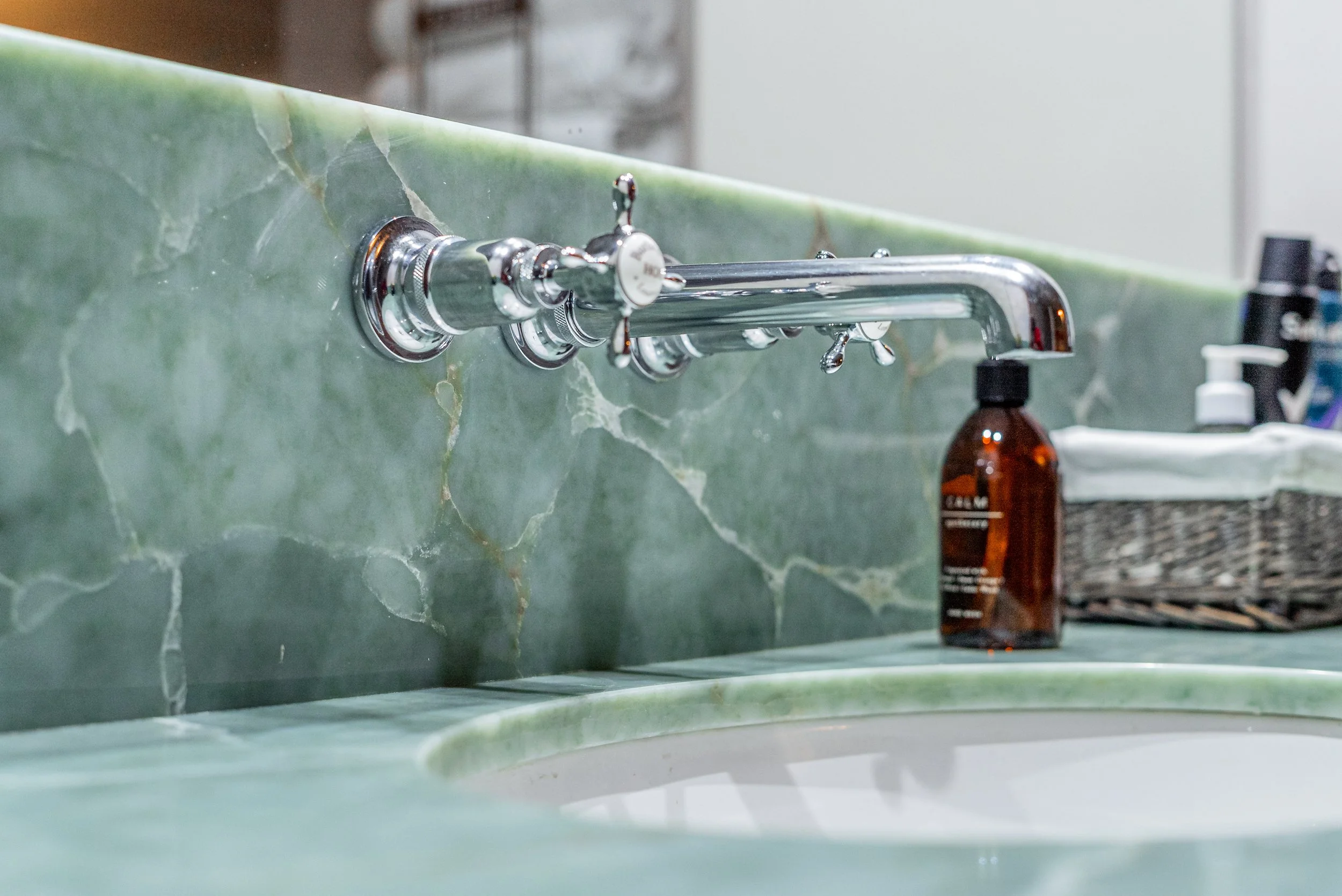 Chrome wall mounted taps over a green stone basin
