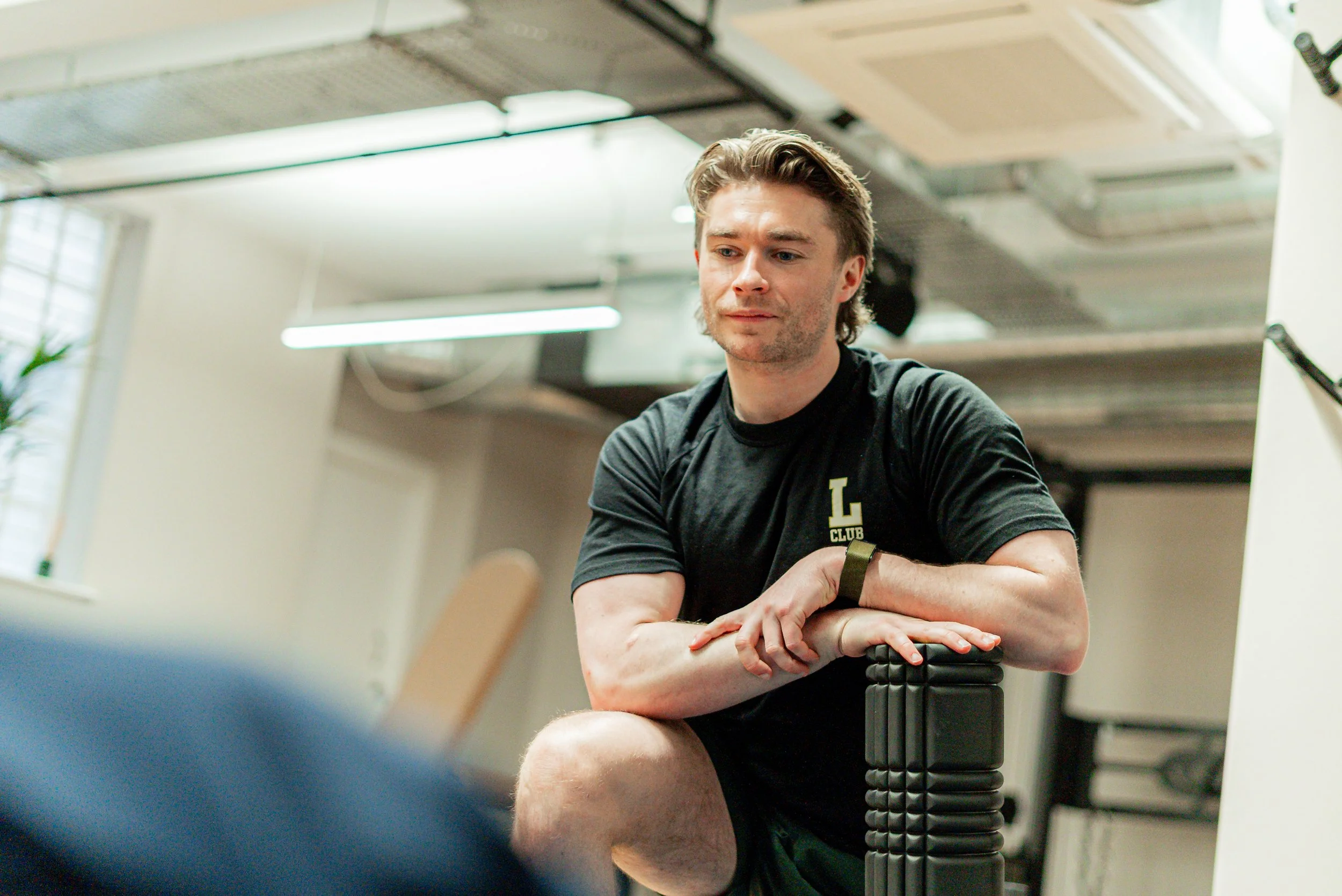 Jake Hitchcock resting on a foam roller between sets, listening to a client