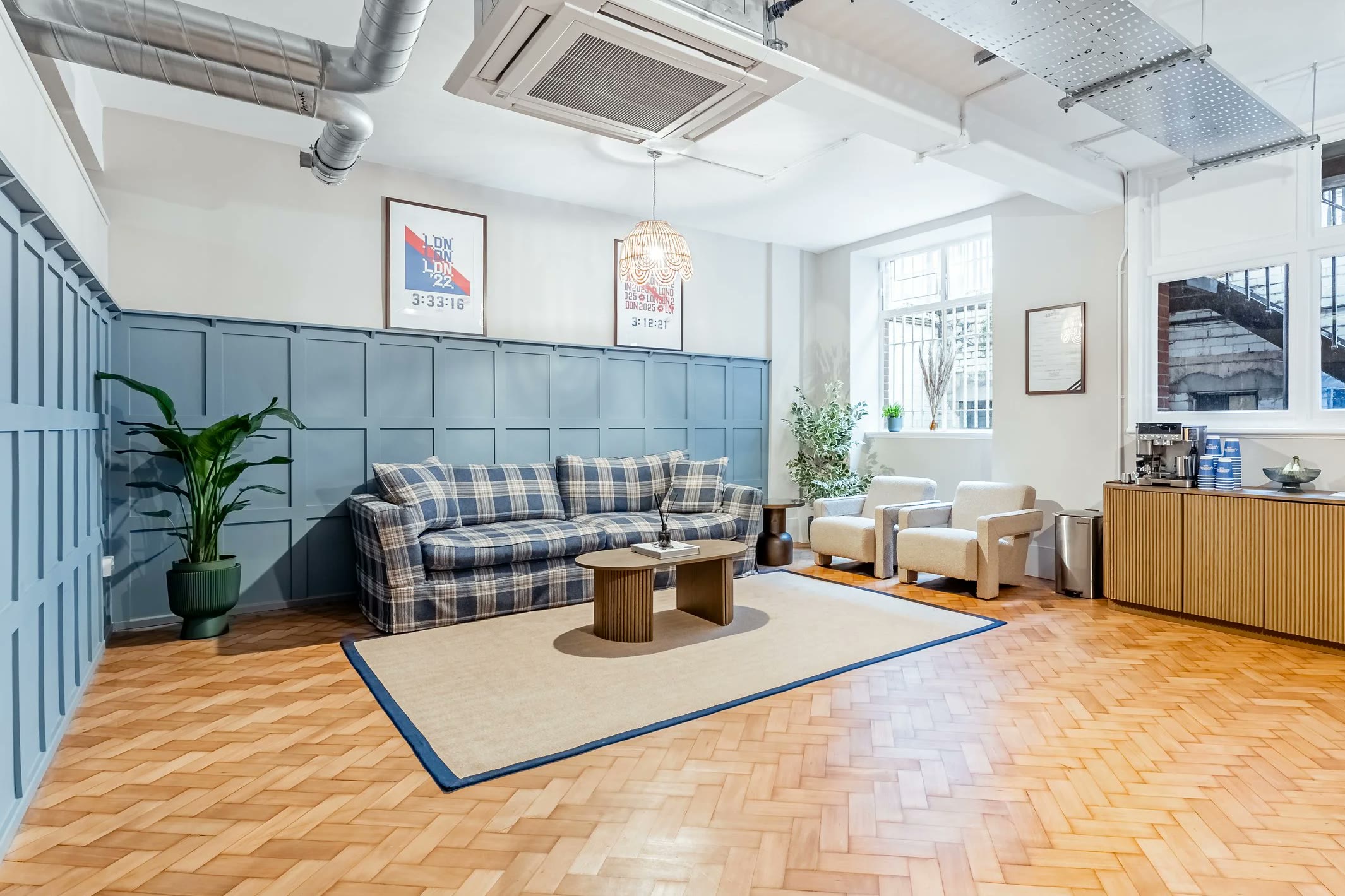 The lounge: blue panelled walls, a tartan sofa, boucle armchairs and a coffee counter