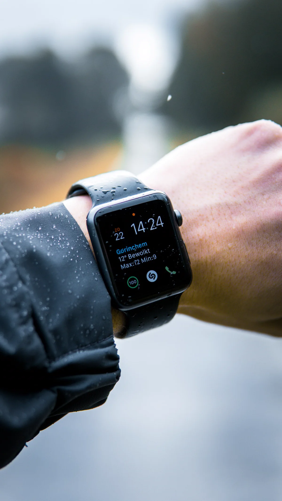 A smartwatch on a wrist, out in the rain